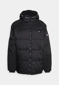 Giacca a vento nera imbottita con chiusura a zip, cappuccio e polsini a costine. Presenta una patch del logo sulla manica sinistra e un design trapuntato con texture contrastanti.