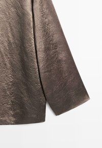 T-shirt à manches longues en tissu métallisé brun foncé texturé avec une finition froissée, présentant une coupe droite et des bords nets.