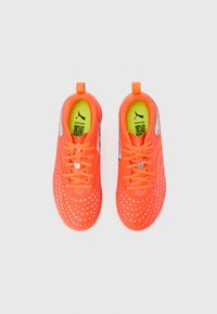 Jaskrawo pomarańczowe buty sportowe z wzorzystą cholewką, teksturowanymi akcentami i neonowożółtymi wkładkami. Posiadają sznurowadła oraz pętelki ułatwiające zakładanie.