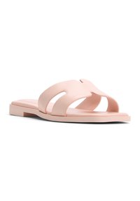 Sandales à glissière rose clair avec orteil ouvert, larges sangles avant et semelle plate. Fabriquées en matériau lisse avec un design minimaliste et des bords arrondis.
