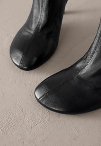 Mustad mustad nahast säärekingad, terava nina ja peene õmbluse detailiga. Sile tekstuur, lame talla, minimalistlik disain, sobivad erinevate riietuste juurde.