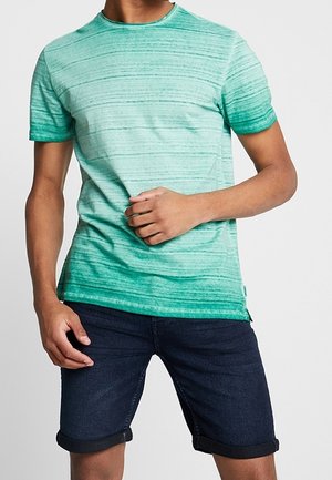 Camiseta verde degradada con rayas horizontales, mangas cortas y cuello redondo, combinada con pantalones cortos de mezclilla oscura.