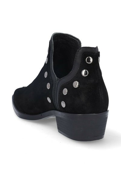 Bota de ante negra hasta el tobillo con tacón bajo y grueso, adornada con tachuelas redondas plateadas a lo largo de los lados y la parte trasera, vista en ángulo sobre fondo blanco.