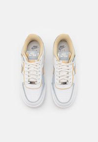 Zapatillas de cuero blancas con detalles en gris, naranja y crema, con parte superior texturizada, diseño con cordones y plantilla acolchada.