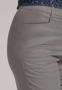 Lichtgrijze pantalon op maat met een gladde textuur, voorzien van een zijzak en een getailleerd ontwerp. De stof is licht rekbaar, wat het comfort verhoogt.