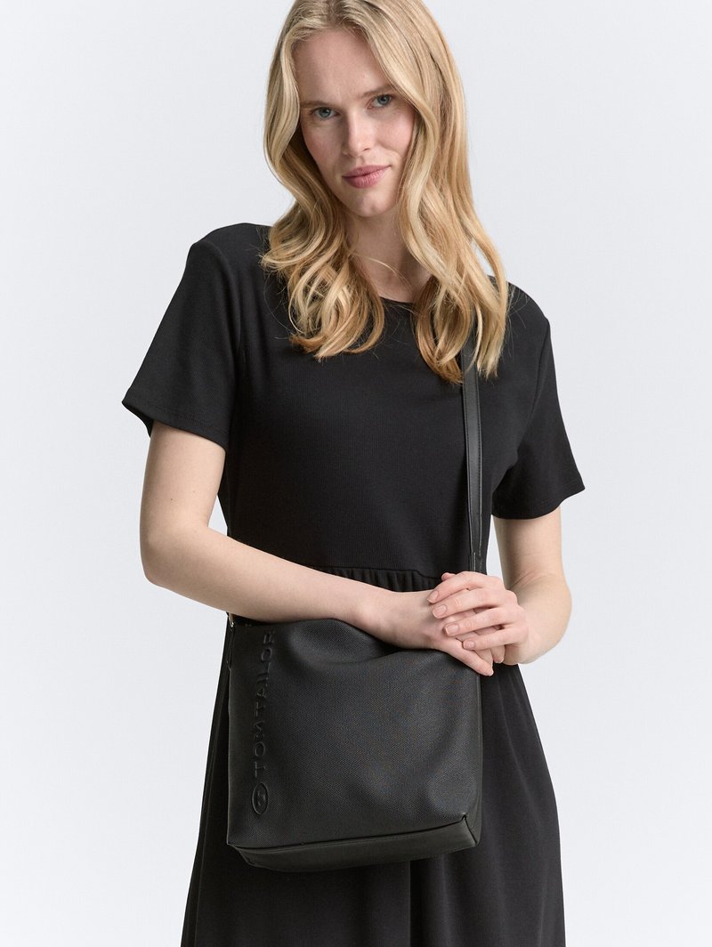 Borsa a spalla nera in materiale sintetico con superficie testurizzata, dotata di logo impresso. Forma rettangolare con tracolla staccabile per maggiore comodità.