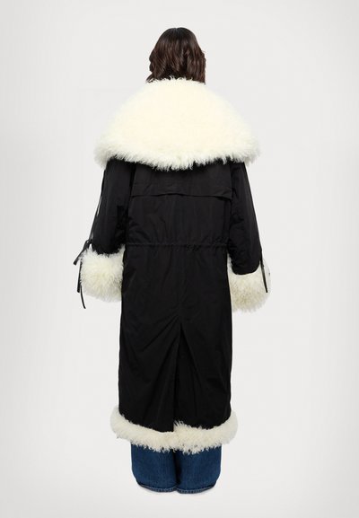 Zwarte parka met kraag en boorden van witte nepbont, trekkoord in de taille, lange mouwen en een split achterontwerp. Soepele stofstructuur overal.