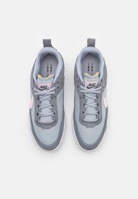 Nike tenisice s gornjim dijelom od svijetlosivog mrežastog materijala, sivi antilop detalji, ružičasti logotip i podstavljena jezik s žutom podlogom.