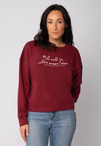 Sweatshirt bordeaux à manches longues, décolleté rond et texte blanc en cursive. Offre une coupe décontractée et une texture douce.