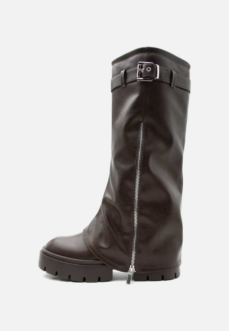 Ψηλή καφέ σκούρα δερμάτινη μπότα με χοντρή σόλα, πλαϊνό φερμουάρ και λουράκι αστραγάλου με ασημένια αγκράφα, απεικονισμένη σε λευκό φόντο.