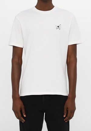 Biała bawełniana koszulka z krótkim rękawem i okrągłym dekoltem, z małym czarnym wzorem czaszki i motyla na lewej piersi.