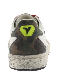 Zapatilla blanca con talón de camuflaje, suela texturizada, logo de acento verde y etiqueta roja en el cuello. Presenta materiales suaves y de ante.