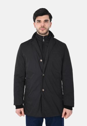 Cappotto leggero nero con chiusura a bottoni, materiale in cotone, colletto con revers e strato interno con zip. Presenta tasche laterali e tessuto texturizzato.