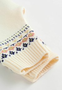 Strikket ærme i cremefarvet med ribbet tekstur. Har broderede blomster- og geometriske mønstre i marineblå, pink og grøn nær manchetterne.