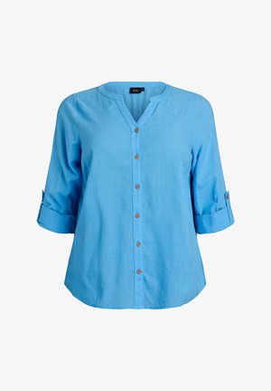 Svetlo modra srajca z gumbi, V-izrezom, tremi četrtinami rokavov in rjavimi gumbi. Iz teksturirane tkanine, z zavihanimi manšetami na rokavih.