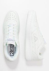 Weiße Sneakers aus Leder und synthetischen Materialien, mit perforierter Zehenkappe, hellblauen Akzenten und einer strukturierten Gummisohle.