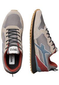 Una coppia di sneakers grigie e beige con lacci neri, interno rosso, logo blu laterale e suole marroni testurizzate, viste dall'alto e di lato.