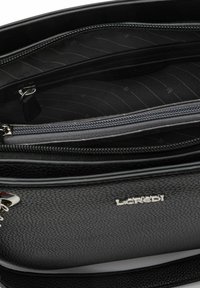 Black leather handbag with textured surface. Features multiple compartments, gray lining, and a silver logo accent. Zipper closures are visible.