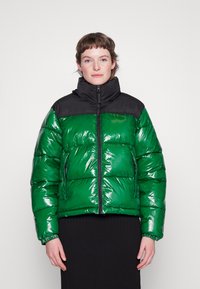 Casaco acolchoado verde e preto, material brilhante, design acolchoado, gola alta, fecho com zipper, bolsos laterais, punhos ajustados, acabamento brilhante.