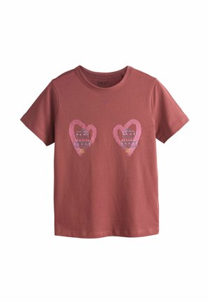 Pruun puuvillane T-särk, kus on kujutatud kaks roosat südamekuju, mille sees on sinise ja punase kleidi mustrid. Ümar kaelus ja lühikesed varrukad.