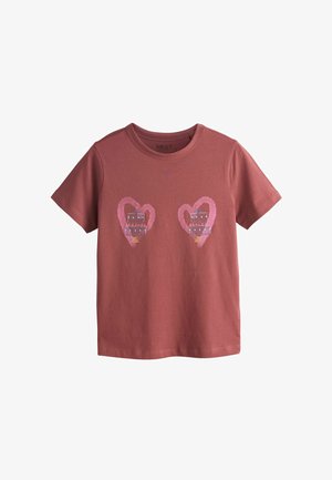 Vinrød T-shirt i bomuld med to lyserøde hjertefigurer med blå og røde kjolemotiver indeni. Rund halsudskæring og korte ærmer.