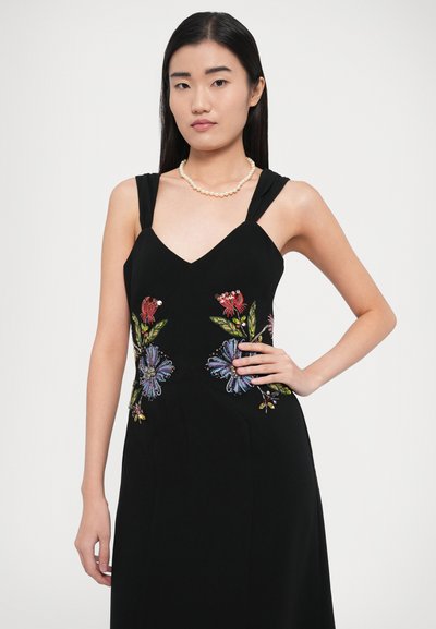 Juoda rankovių neturinti suknelė su spalvotu gėlių siuvinėjimu ant liemens. Audinys yra lygios tekstūros, subtiliai struktūruoto kirpimo.