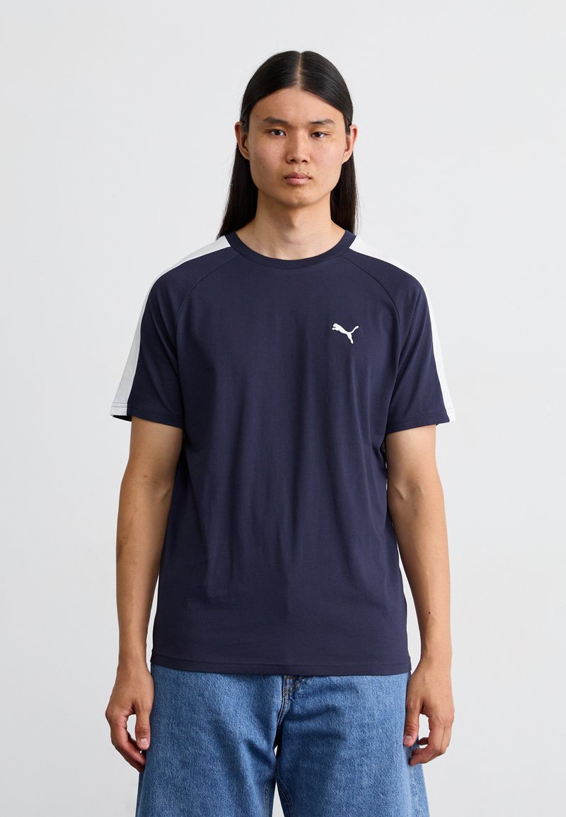 Marineblå bomulds T-shirt med korte ærmer, med hvide detaljer på skuldrene og et lille hvidt logo på brystet.