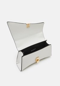 Weißes Clutch aus Leder mit Krokodilprägung, goldfarbener Verschluss, schwarzes Innenfutter und leicht konische Form. Offen, mit sichtbarem Innenraum.