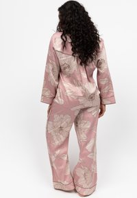 Rosa Pyjama-Set mit Blumenmuster, bestehend aus locker sitzender Hose und langärmligem Oberteil mit glatter Textur und cremefarbenen Blumenmustern.