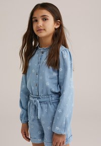 Világoskék, virágmintás farmerruha hosszú ujjakkal, gombos részletekkel, elasztikus derékkal és illeszkedő sortokkal.