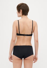 Svart bh med tynne justerbare stropper og hekklukking, kombinert med matchende høytlivsunderbukser. Glatt tekstur, minimalistisk design, ingen mønstre.