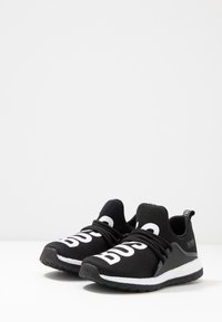 Zapatillas deportivas negras con suelas blancas y un audaz texto en blanco "BOSS" en la parte superior, con cordones negros y una pestaña en el talón.