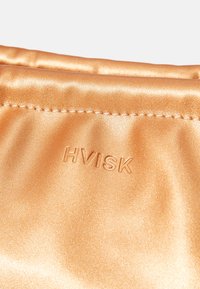 Metallic oranžinė rankinė su lygiu, blizgiu paviršiumi, dekoruota įspaustu "HVISK" prekės ženklu ir matomais siūlų detalėmis.
