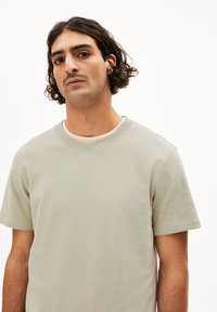 Hellgraues Baumwoll-T-Shirt mit rundem Ausschnitt, kurzen Ärmeln und glatter Textur. Hat einen lässigen Schnitt. Keine sichtbaren Muster oder Akzente.