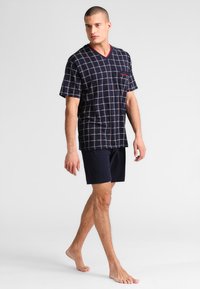 Marine checkered pyjama set met een korte mouwen V-hals top met een zak, gecombineerd met bijpassende marine shorts. Soepele stoftextuur.