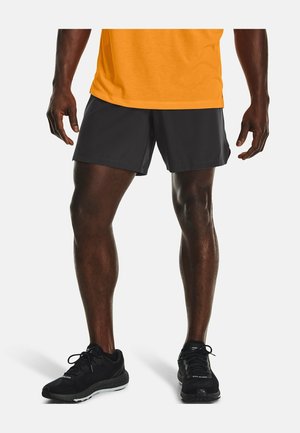 Shorts de sport noirs avec une texture lisse, associés à un t-shirt orange à manches courtes et des baskets noires, affichant un design sportif.