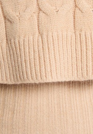 Maglione lavorato a maglia in morbida lana beige, con un motivo a treccia testurizzato nella parte superiore e orlo a coste. Texture liscia con un aspetto caldo.