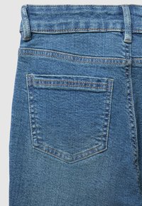 Blaue Jeans aus Denim mit klassischer Schnittführung, ausgestattet mit einer einzelnen Gesäßtasche mit genähtem Rand und strukturierter Oberfläche.