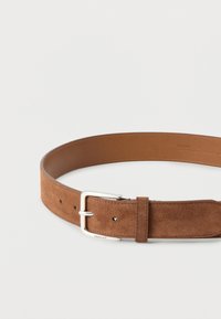 Καφέ ζώνη από σουέντ με λεία επένδυση από δέρμα, που διαθέτει ασημένια μεταλλική πόρπη και πολλαπλές τρύπες για ρύθμιση. Μαλακή υφή και ανθεκτικός σχεδιασμός.