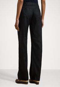 Black linen wide-leg pants with two back pockets. The fabric has a soft texture, and the design features a high waist.