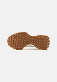 Schuhsohle mit erhöhten, kreisförmigen Profilierungen in einem einheitlichen Muster, in hellbrauner Farbe, auf einem weißen Hintergrund fotografiert.