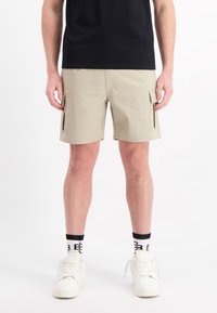 Beige cargoshorts met zijzakken, gemaakt van lichtgewicht stof, met een rechte snit en zonder zichtbare patronen. Gestyled met een zwart shirt.