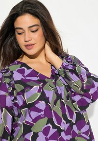 Blusa a maniche gather con scollo a V, con un motivo floreale viola e verde e dettagli a volant; tessuto leggero e testurizzato.