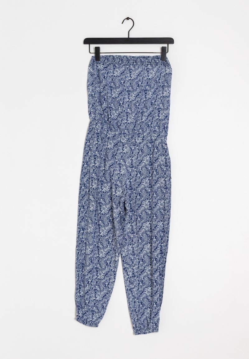 Combinaison bustier imprimée paisley bleue et blanche avec taille élastiquée et bas de jambes aux chevilles, suspendue sur un cintre noir.