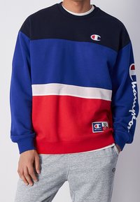 Farbblockierter Sweatshirt in Marineblau, Königsblau und Rot. Verfügt über einen Mesh-Streifen und ein gesticktes Logo. Rippbündchen und Saum.
