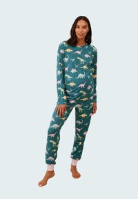 Grön pyjamasset med långa ärmar och elastiska muddar, pryds av färgglada dinosauriemönster i rosa, gult och blått, tillverkad av mjukt tyg.