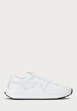 Baskets blanches à profil bas avec dessus en cuir et tissu, lacets blancs, semelle épaisse et logo discret de la marque sur le côté.