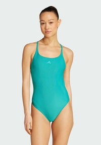Tyrkysový jednodílný plavky s tenkými ramínky, vroubkovanou texturou a malým bílým logem na hrudi. Hladká látka, decentní střih na nohách.