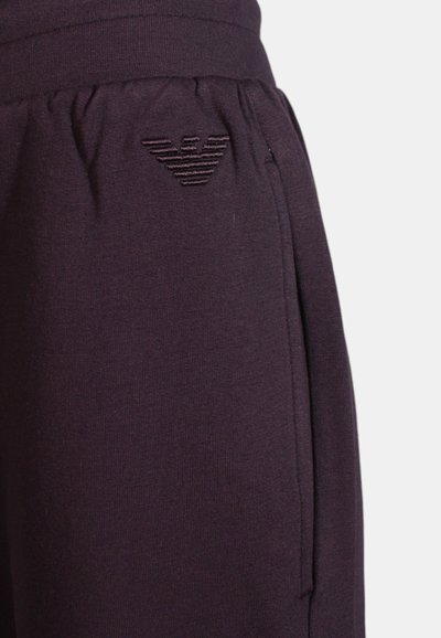 Pantaloni sportivi viola realizzati in tessuto morbido, con una cintura elastica e un piccolo logo ricamato sul lato. Design semplice con tasche laterali.
