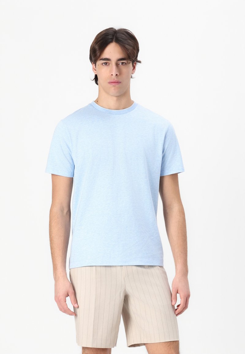 Lyseblå bomull T-skjorte med rund hals og korte ermer, kombinert med beige stripete shorts. Glatt tekstur og enkelt design.